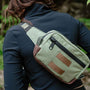 Lane sling bag shown in green duck cloth and waxed canvas on women walking through woods