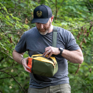 Hayden sling bag shown in olive and orange.  This bag has a large center pocket perfect to fit a Nalgene water bottle.  Great for outdoor use and hiking.
