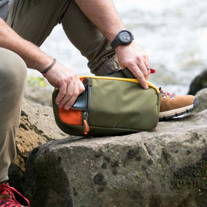 Hayden sling bag shown in olive and orange.  This bag has a front fleece lined pocket perfect for your phone.  Great for outdoor use and hiking.