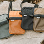 NBS crossbody bags in foliage, orange, black and brown laying on a rock