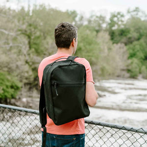 Man wearing 21L black cordura backpack watching a waterfall