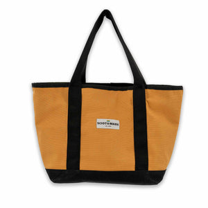 Darby Tote in gold duck cloth & black waxed canvas: Spacious main compartment, interior pockets, D-ring. Sturdy, easy to clean. Made in the USA. Size: 13" L x 7" W x 12" H.