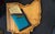 Skip wallet is a minimalist front pocket wallet.  Outside color is teal and inside color is yellow.  Wallet is laying on an Ohio catchall.  