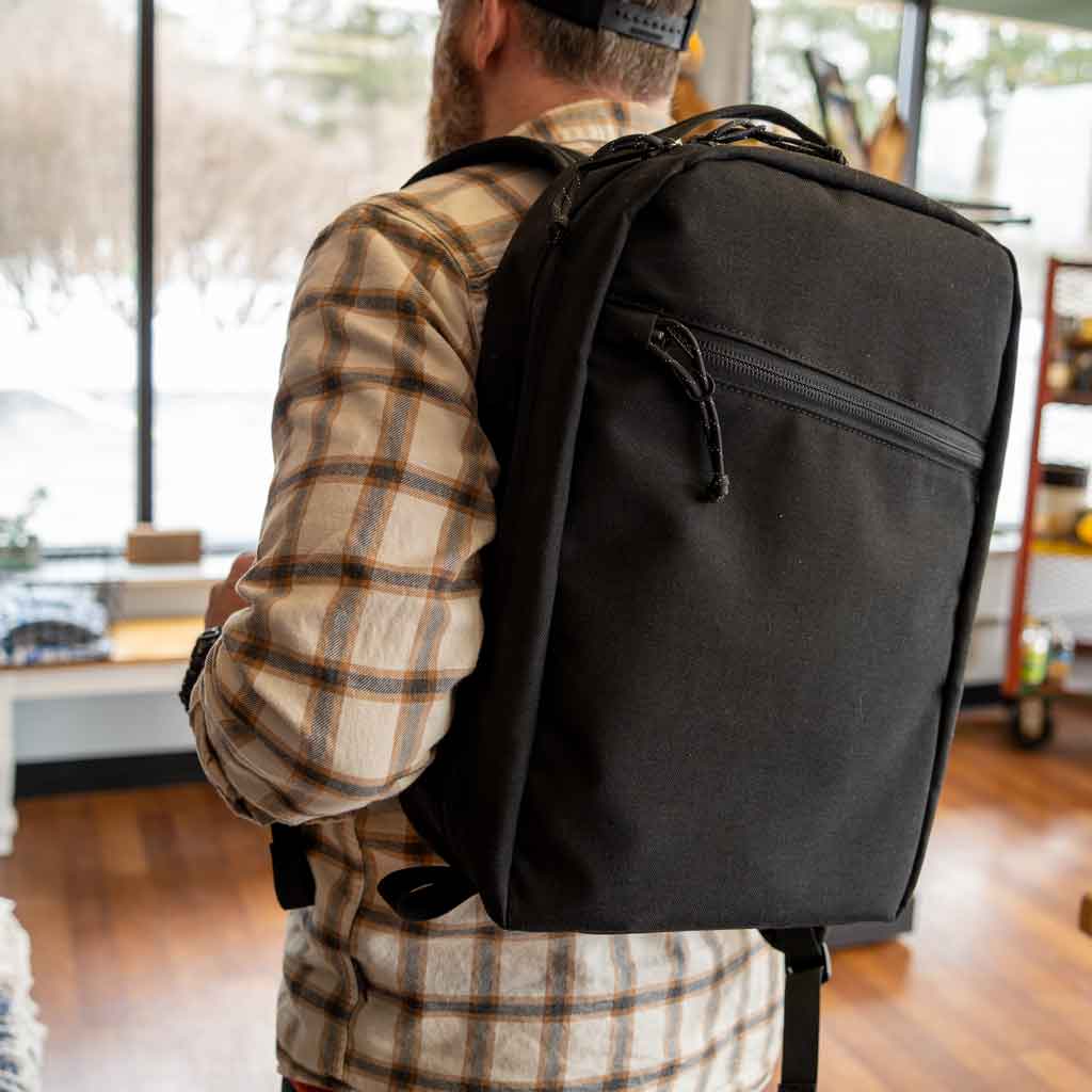 Man wearing a 21L black travel backpack handmade by Scioto Made.