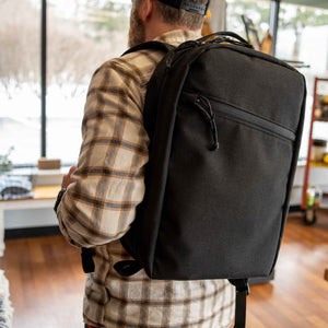 21L 1000D Cordura Backpack in all black. Pictured is man wearing backpack.