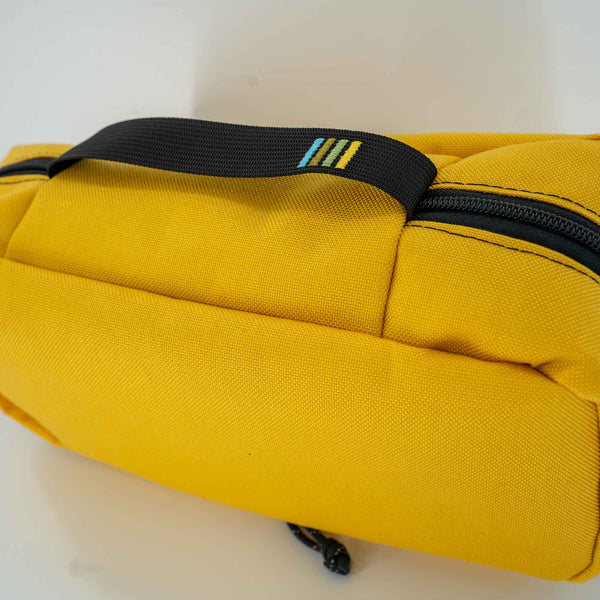 This 4L yellow packing cube is made with durable 1000D Cordura and lined with bright 400D pack cloth.  Inside there are two internal mesh pockets to make organization simple. Close up view of the exterior handle with the Scioto Made stripes embroidered on it. 