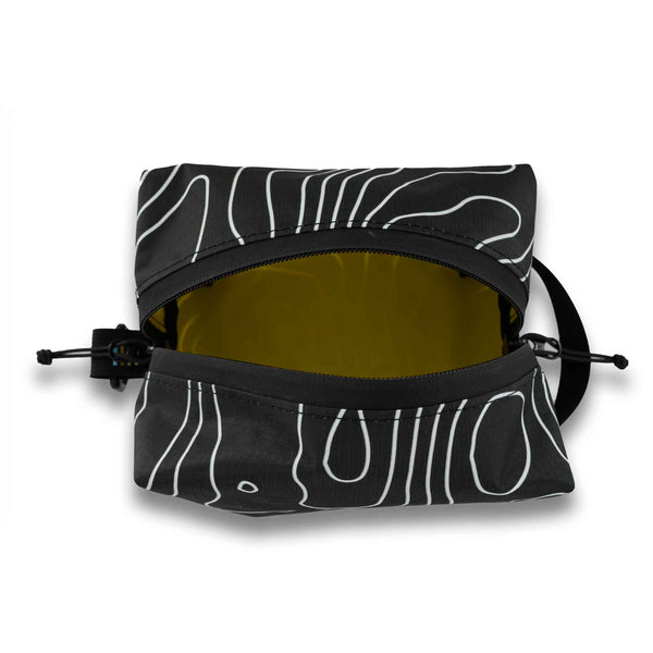 Handmade with premium materials this dopp kit is built to last throughout your travels and beyond. It will hold all your essential toiletry and accessory needs with ease.  Made with an aqua guard zipper to protect your items from the elements while exploring the great outdoors. Outside material is x-pac in a black and white topo design.  The inside is lined with yellow pack cloth. Made in Ohio.