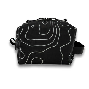 Handmade with premium materials this dopp kit is built to last throughout your travels and beyond. It will hold all your essential toiletry and accessory needs with ease.  Made with an aqua guard zipper to protect your items from the elements while exploring the great outdoors. Outside material is x-pac in a black and white topo design.  The inside is lined with yellow pack cloth. Made in Ohio.