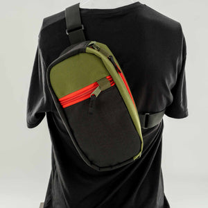 The Hayden urban sling bag in black and olive with red zipper. Front View
