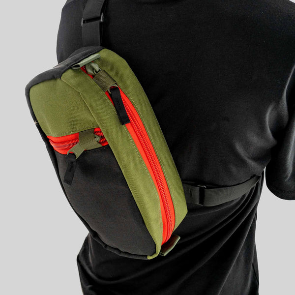 The Hayden urban sling bag in black and olive with red zipper. Front View