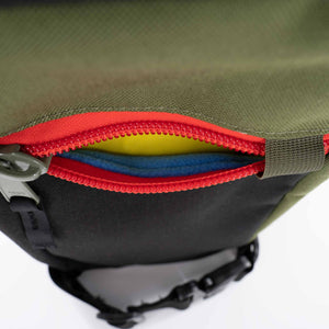 The Hayden urban sling bag in black and olive with red zipper. Fleece lined front pocket.